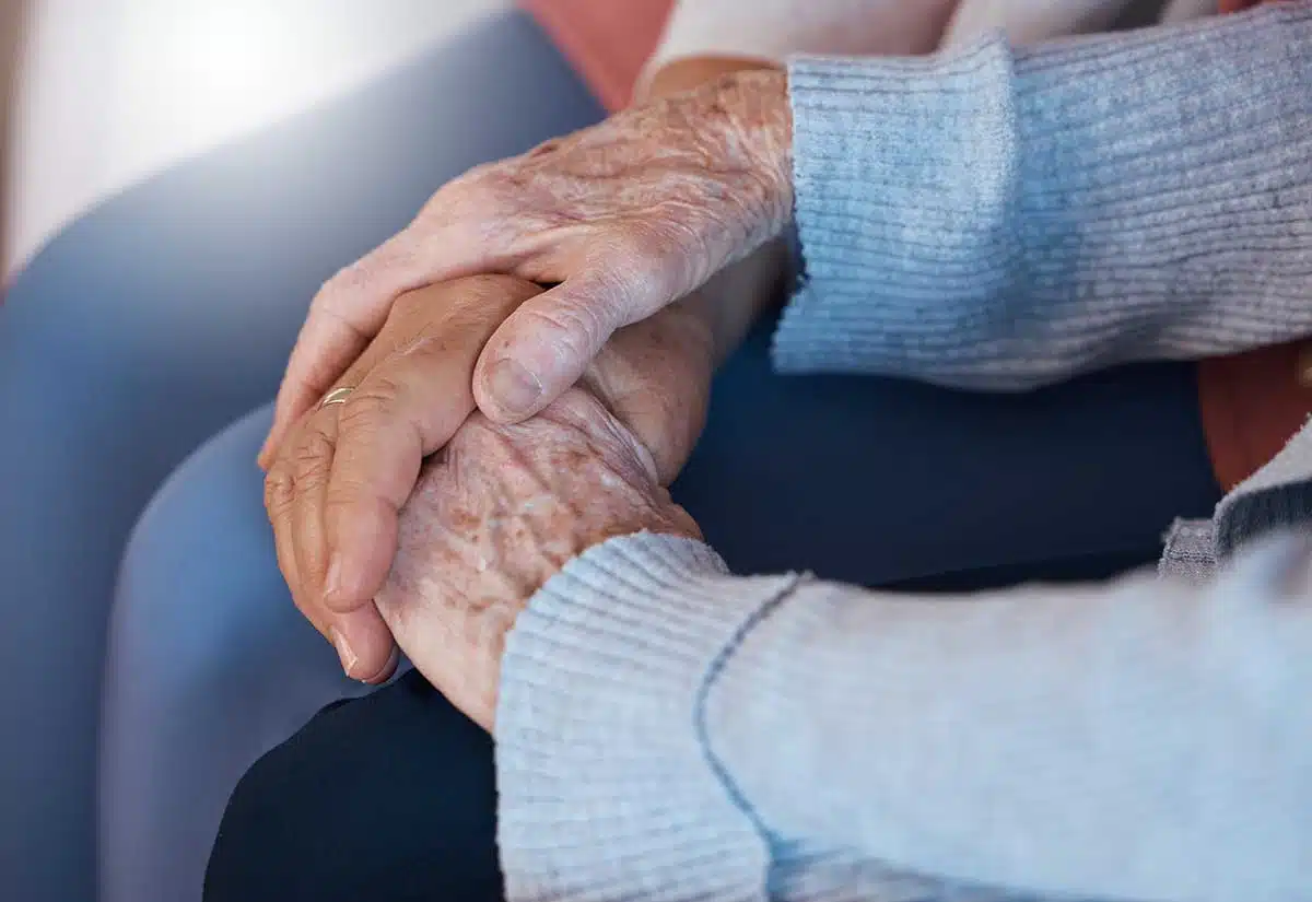 Caregiver holding hands of an elderly person